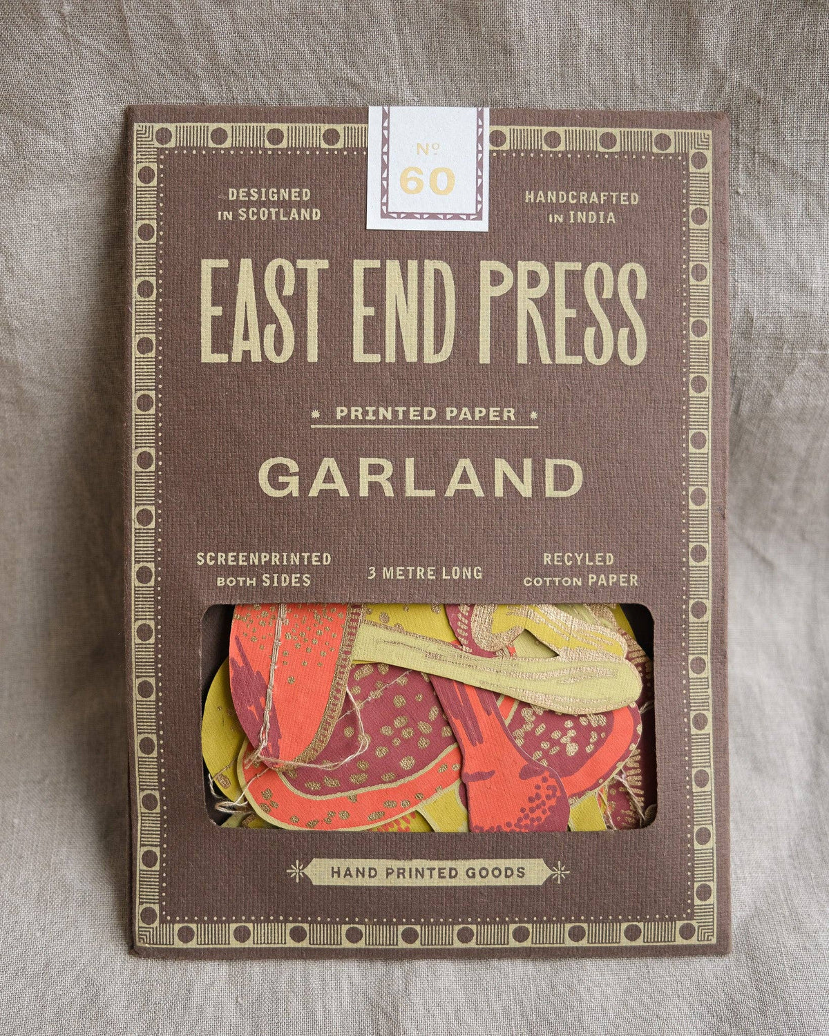 East End Press Mushroom Sewn Garland in brown packaging on textured beige fabric.