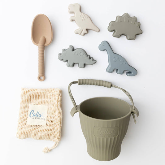 Children's sand toy set with a bucket, spoon, mesh bag and dinosaur-shaped molds on a white background.