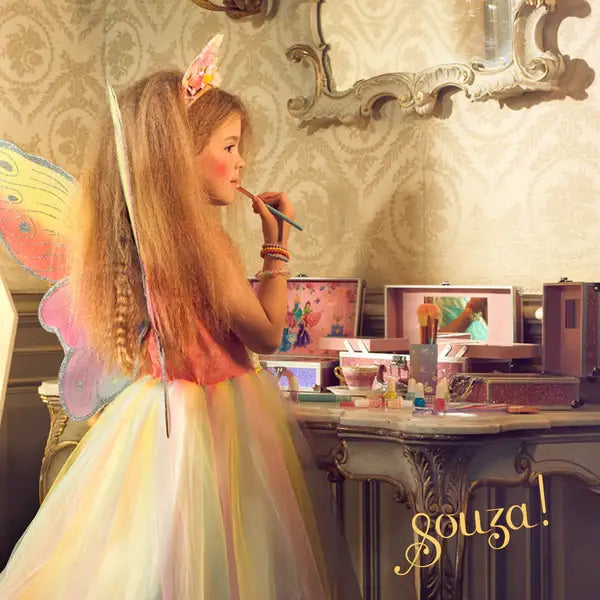 Young girl in a fairy costume applying makeup in front of a mirror