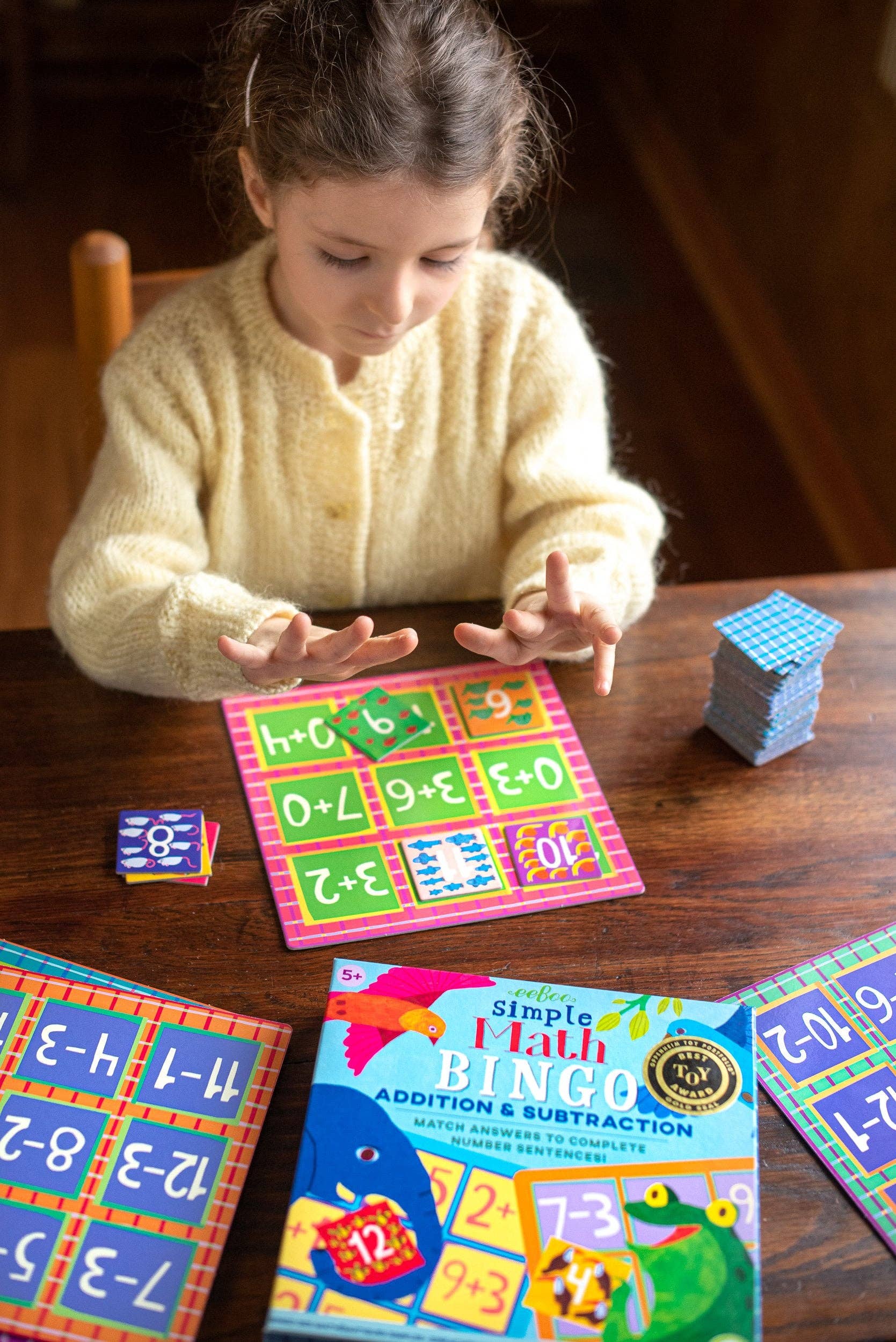 Child playing with educational math cards on a wooden table