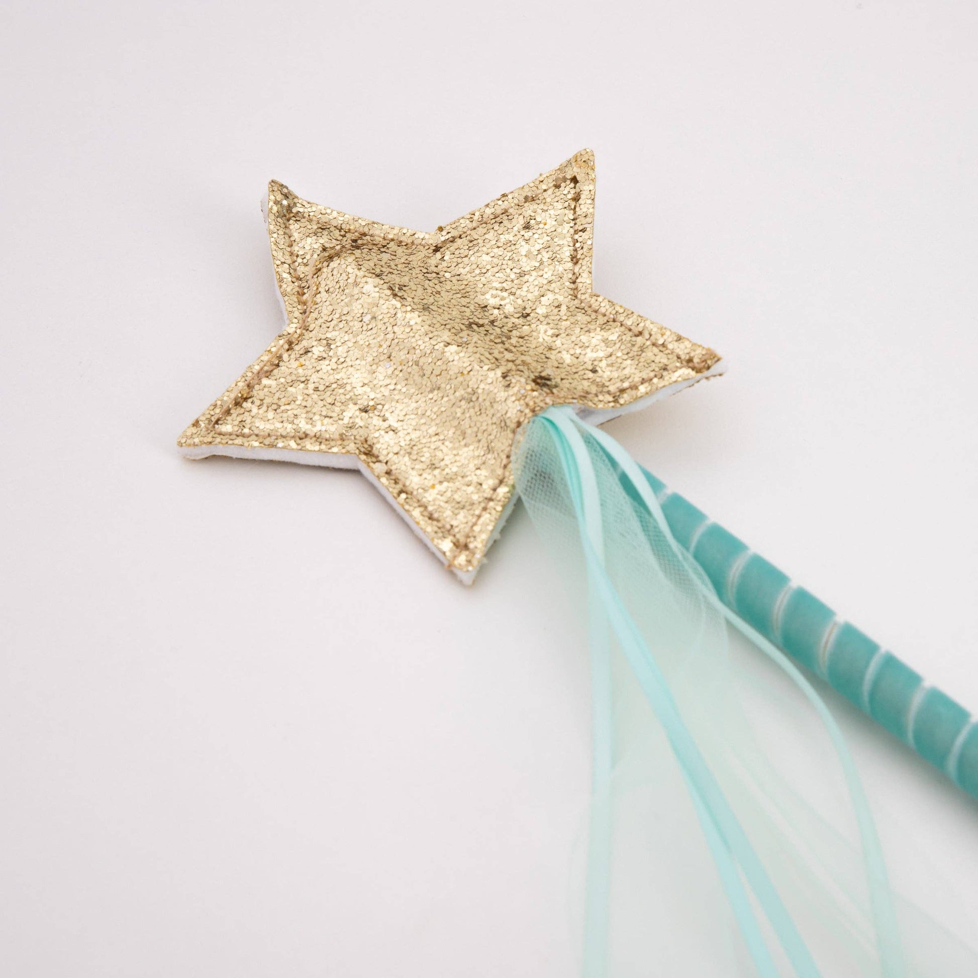 Gold star wand with a blue ribbon on a light gray background