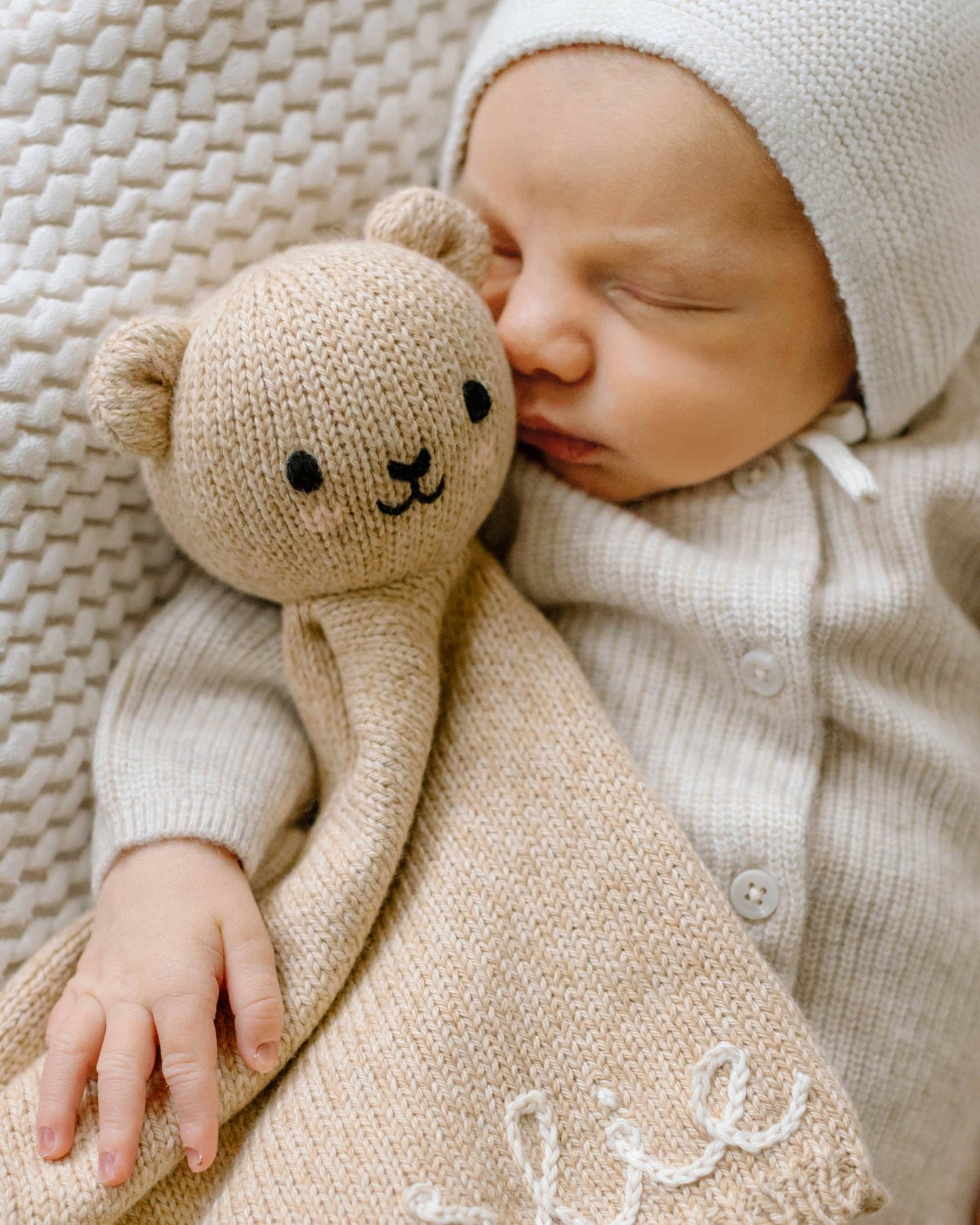 Newborn baby sleeping with a beige knitted lovey