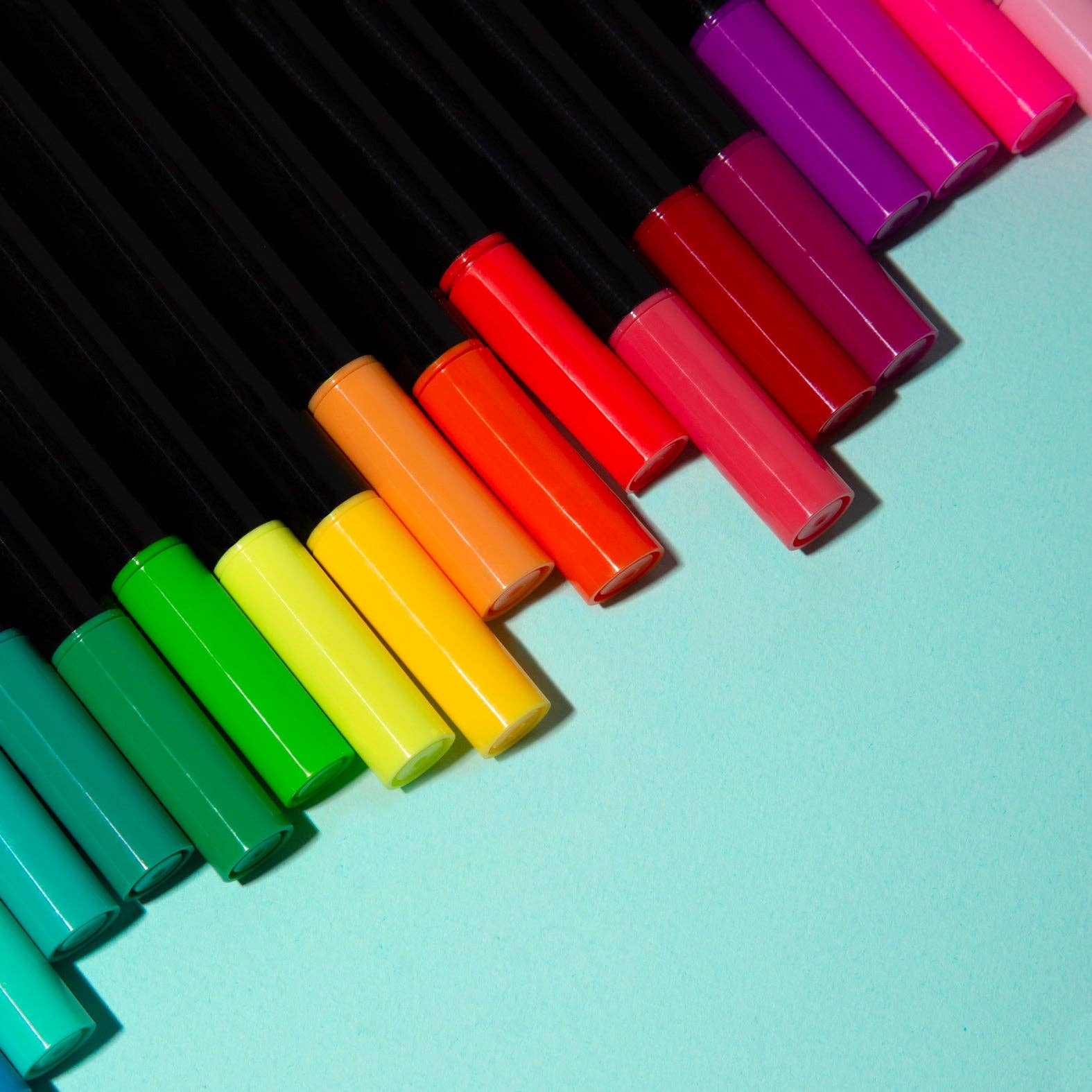 Colorful markers arranged in a diagonal pattern on a light blue background