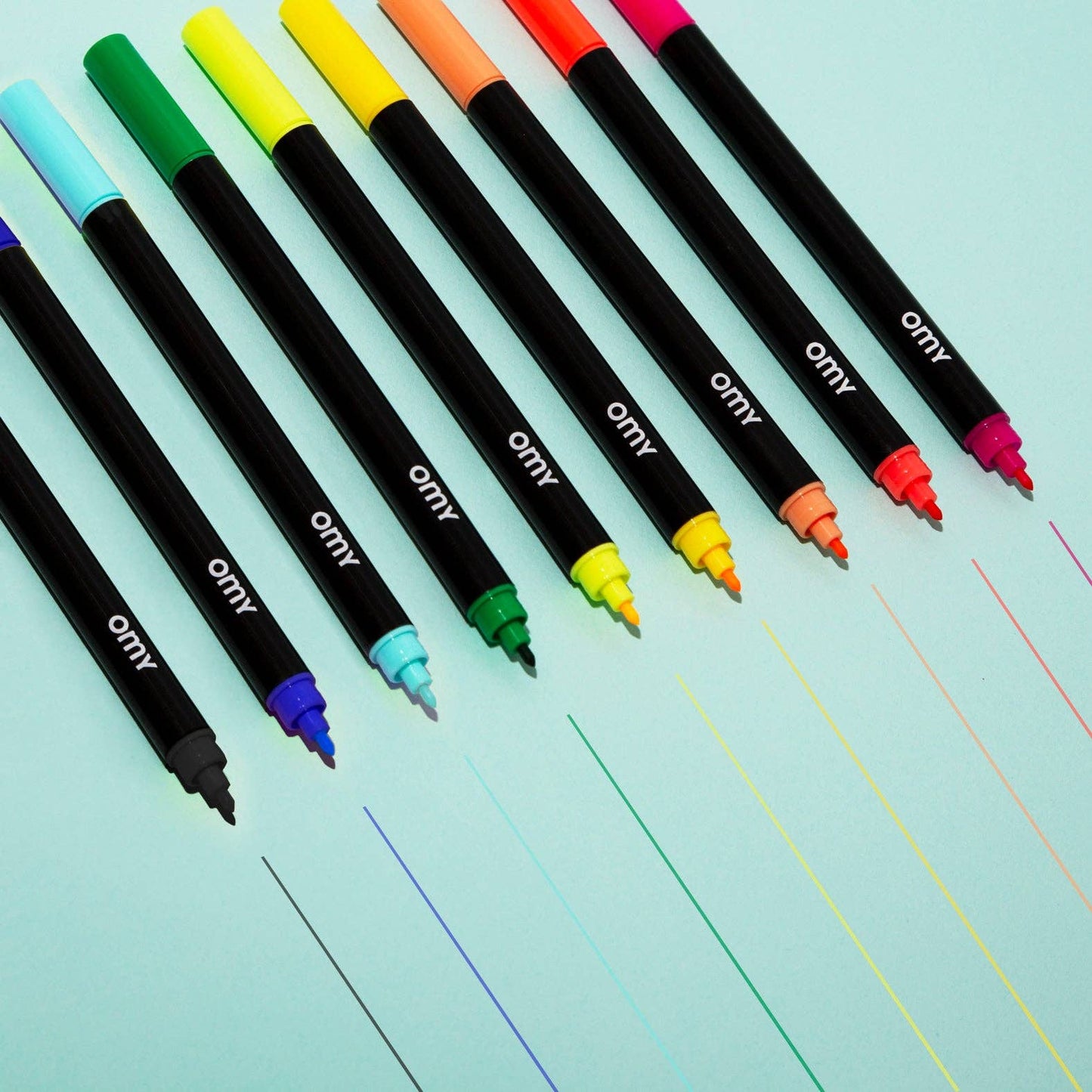 Set of colorful markers on a lined notebook page with 'omy' branding.