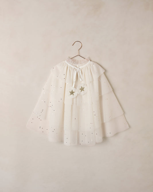 White tulle cape with star details on a hanger against a beige wall
