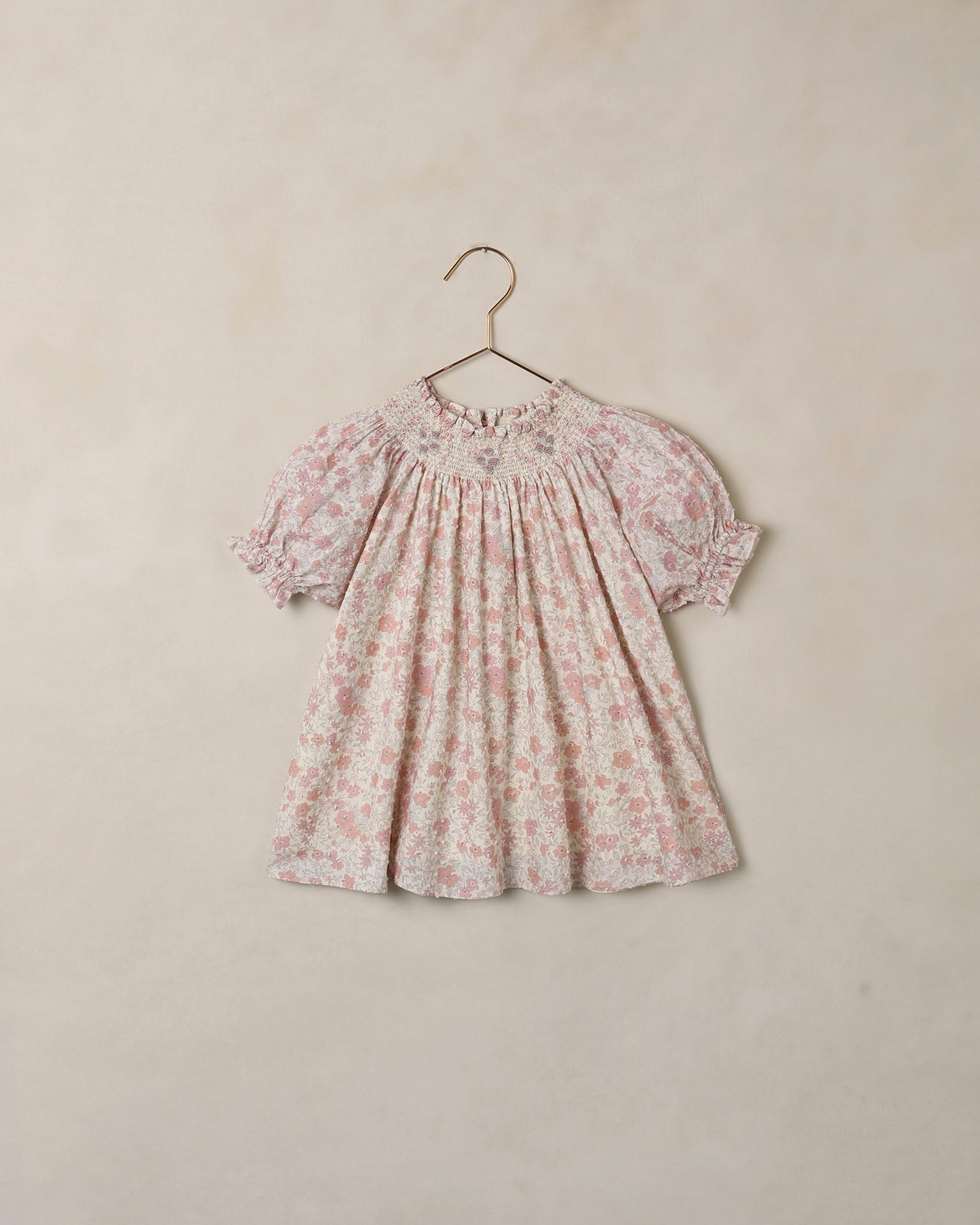 Floral dress on a hanger against a beige background