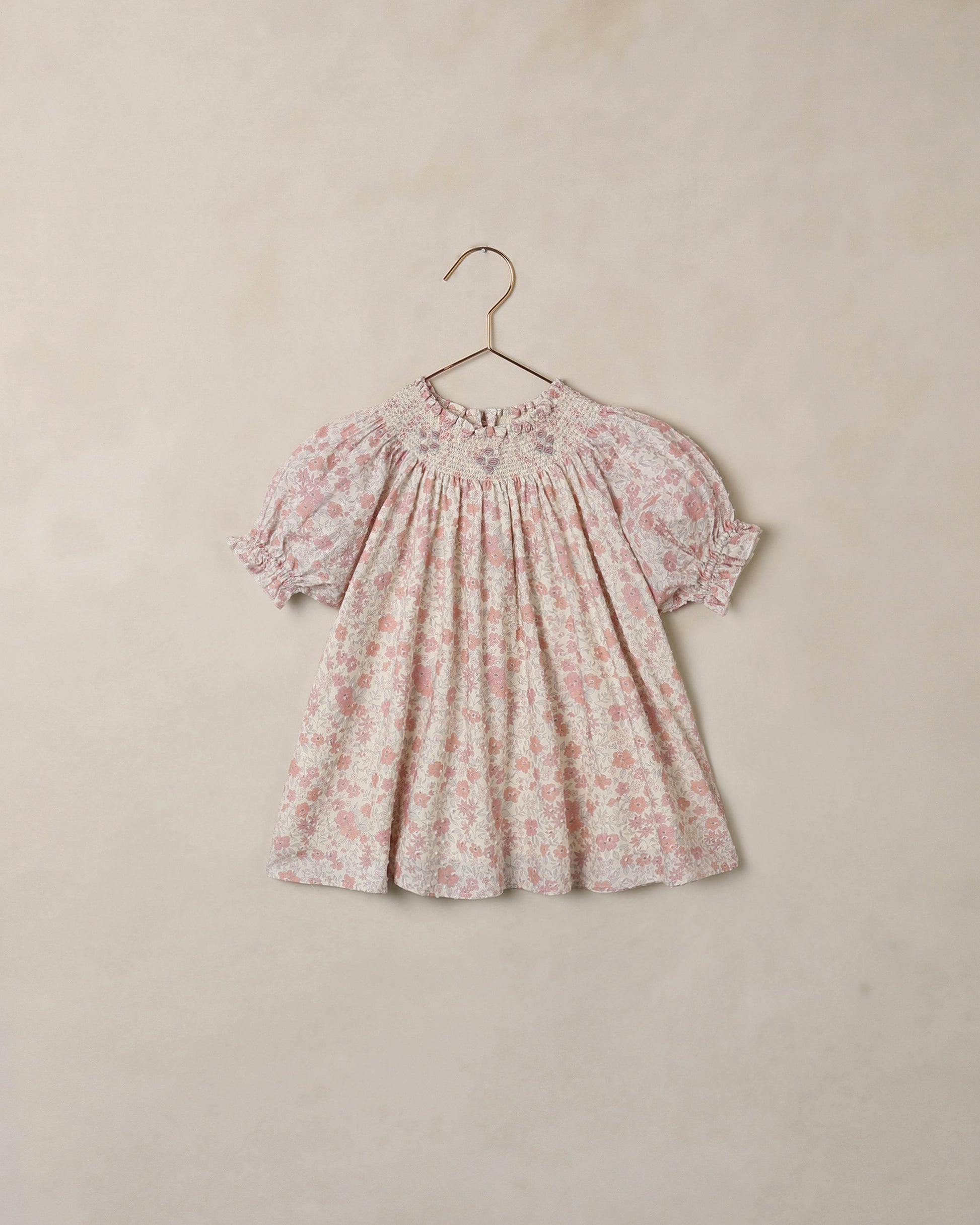 Floral dress on a hanger against a beige background