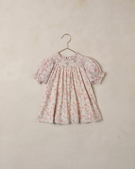 Floral dress on a hanger against a beige background