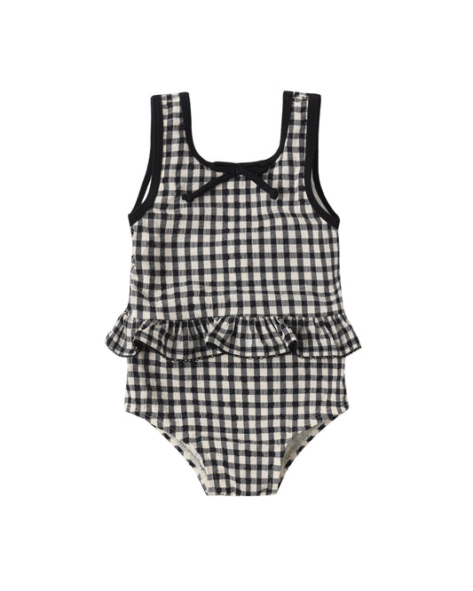 Black and white checkered children's swimsuit with ruffled details on a white background