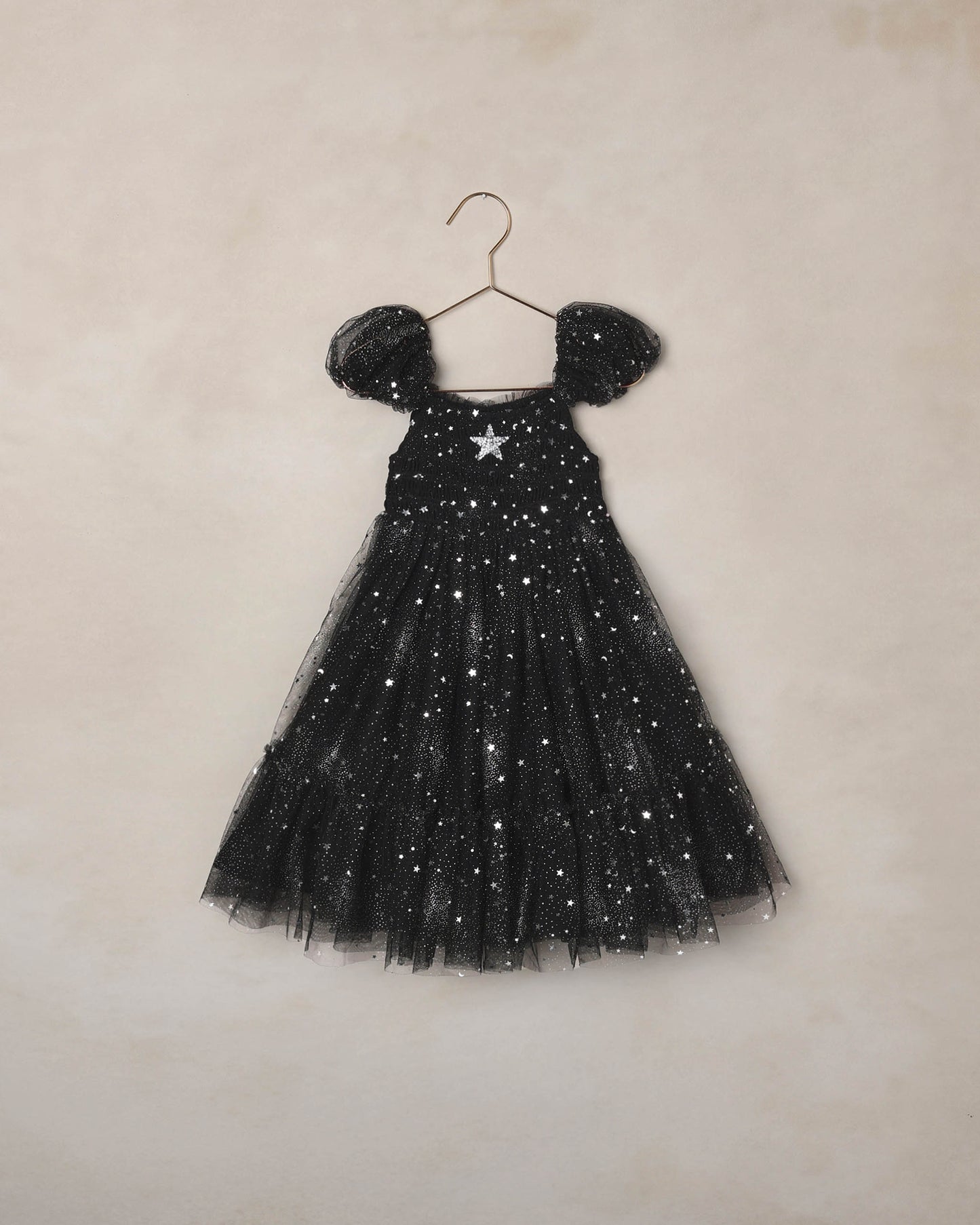 Children's black dress with silver starts on a beige background