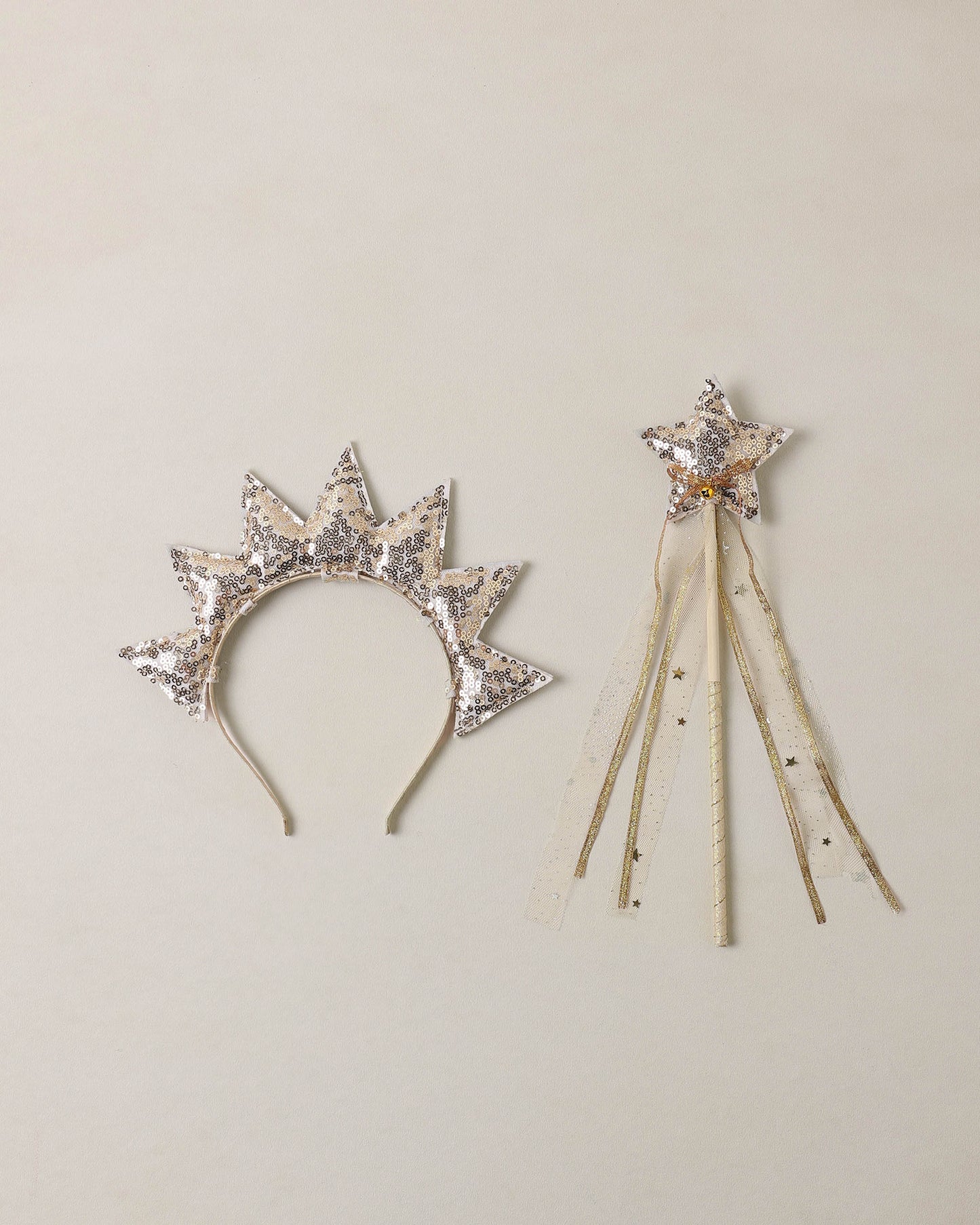 Sun crown and gold wand on beige background