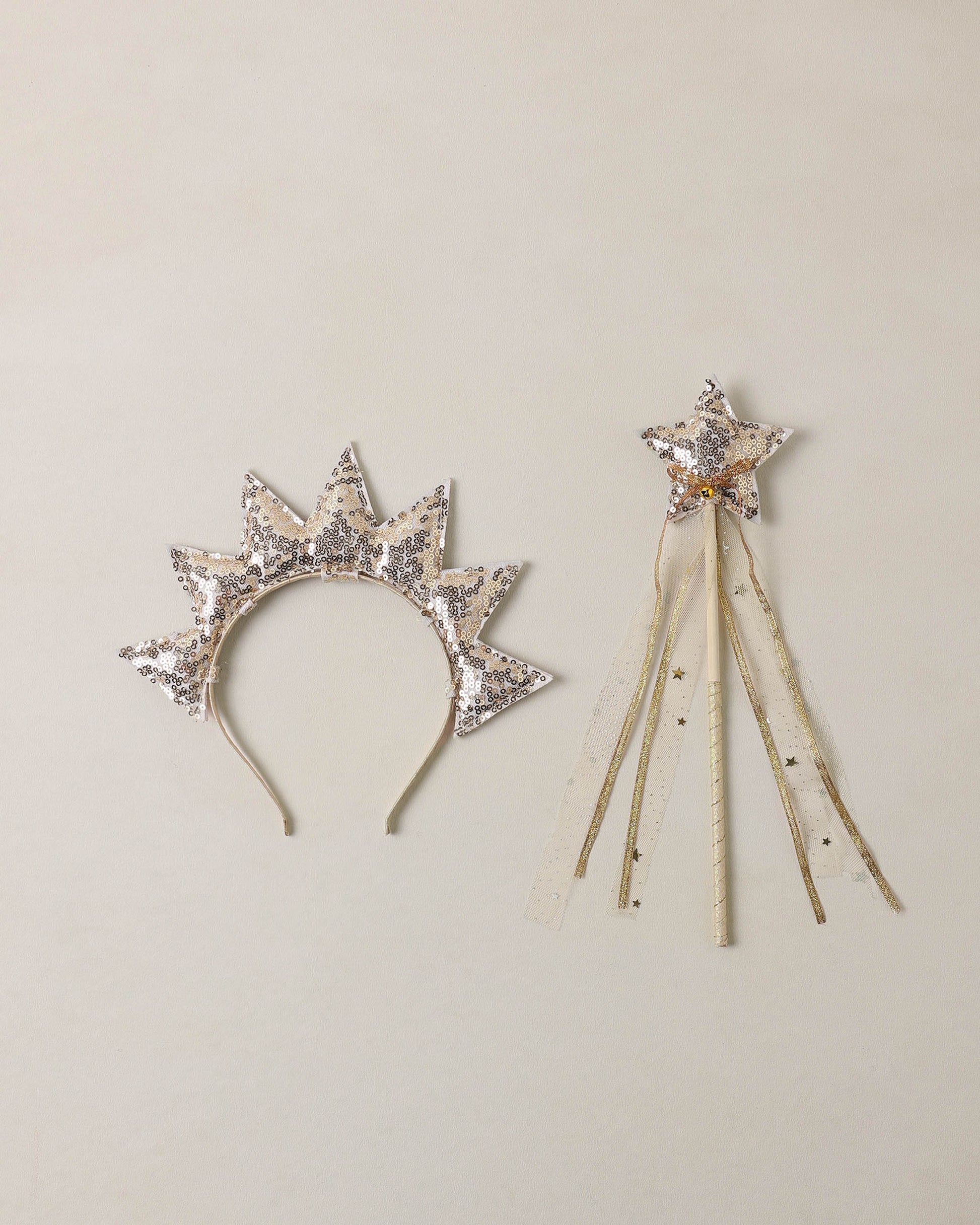 Sun crown and gold wand on beige background