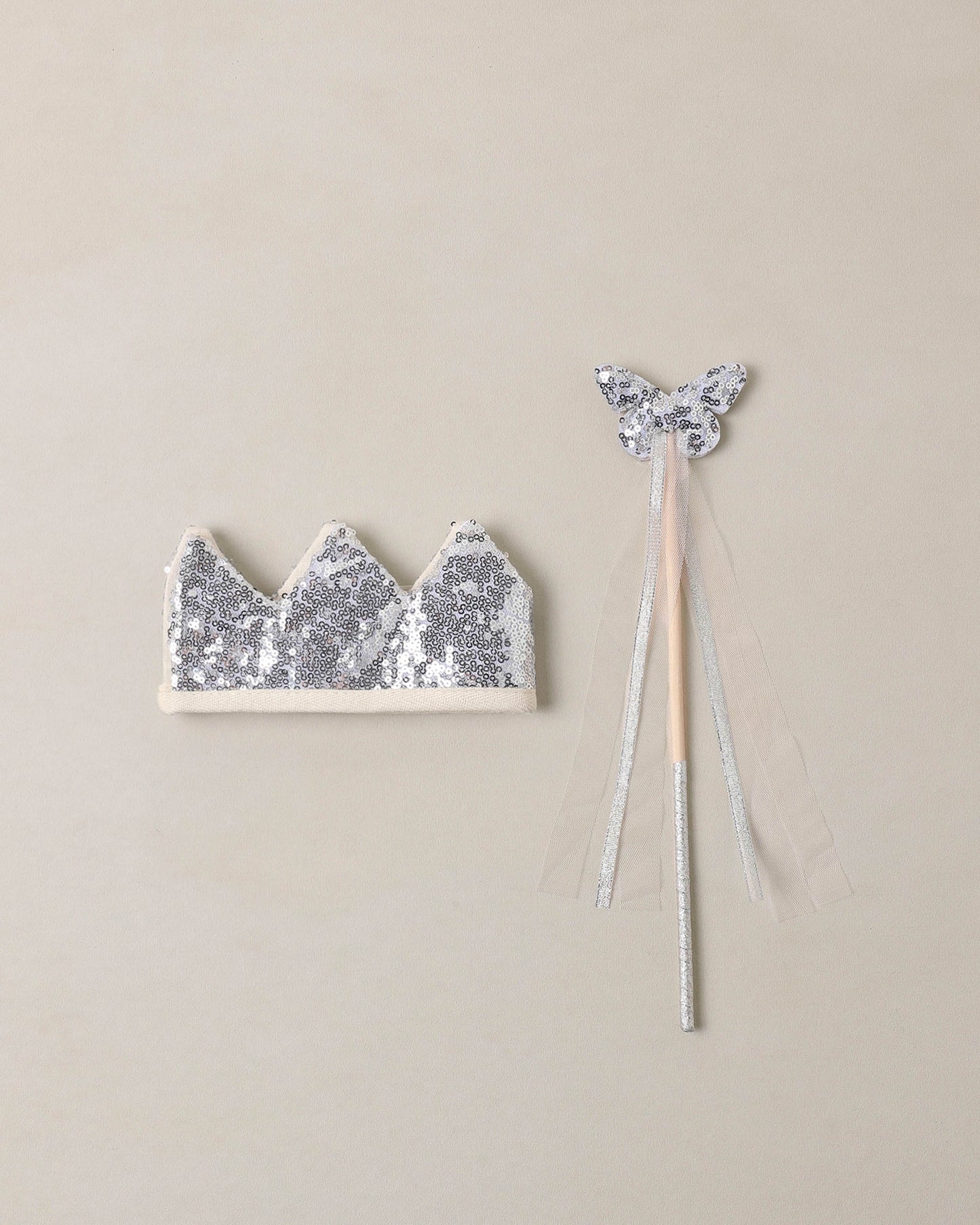 silver sequin wand and crown on a beige background