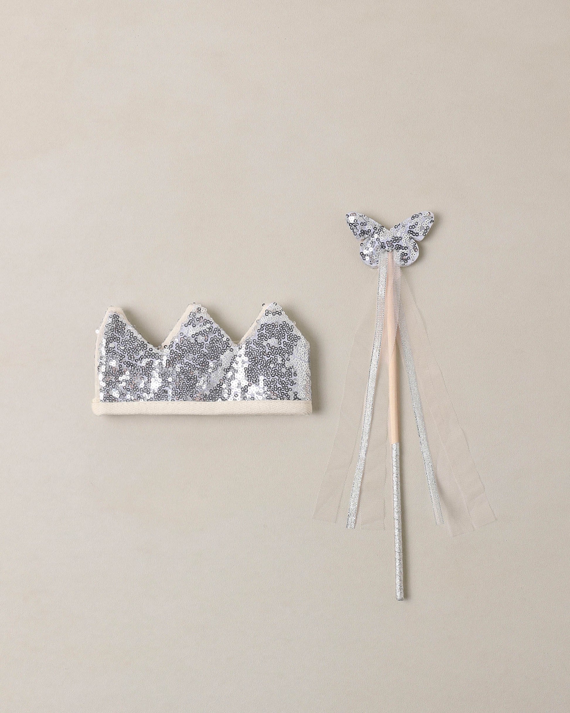 silver sequin wand and crown on a beige background
