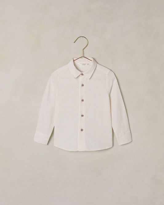 White button down collared shirt on a hanger against a beige background